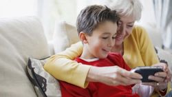 An elderly woman and her grandson watch a video on a cell phone