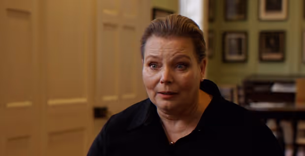 Joanna Scanlan sitting indoors during a poetry reading.